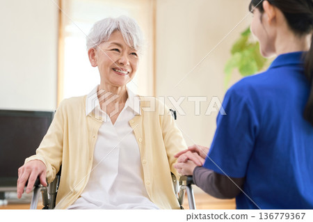 Asian visiting caregiver holding a senior's hand 136779367
