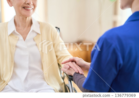 Asian visiting caregiver holding a senior's hand Asian visiting caregiver holding a senior's hand 136779369