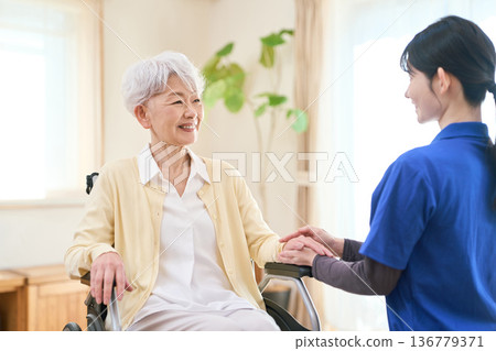Asian visiting caregiver holding a senior's hand 136779371