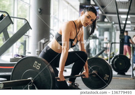 Ready to lift the barbell. Beautiful woman is at the gym Ready to lift the barbell. Beautiful woman is at the gym 136779493