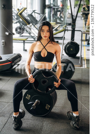 Showing, holding heavy weight. Beautiful woman is at the gym 136779522