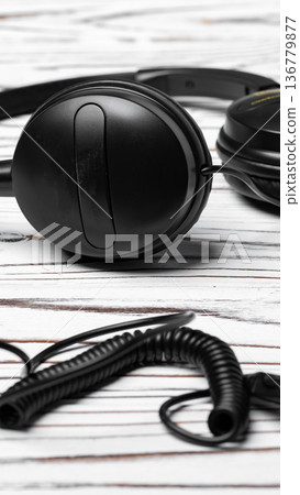 Headphones placed on a wooden surface with a coiled cable nearby during daytime 136779877