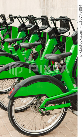 Green bikes lined up in a city bike-sharing station during daylight hours Green bikes lined up in a city bike-sharing station during daylight hours 136779884