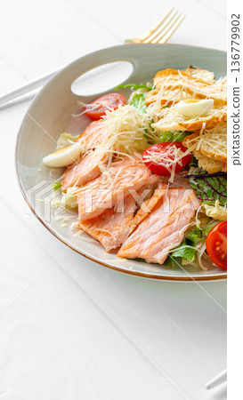Fresh salmon salad served on a plate with greens, tomatoes, and cheese at a dining table Fresh salmon salad served on a plate with greens, tomatoes, and cheese at a dining table 136779902