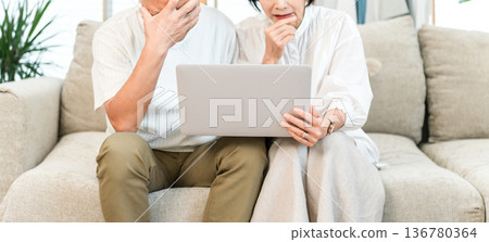 Senior couple shocked while looking at a computer screen Senior couple shocked while looking at a computer screen 136780364