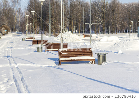 Array of the benches in a park covered with snow Array of the benches in a park covered with snow 136780416