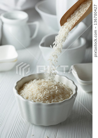 Raw organic rice is poured in white bowl. Raw organic rice is poured in white bowl. 136780427