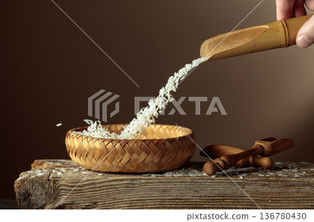 Rice is poured into a wicker bowl. 136780430