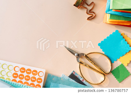 Scissors, planner and colorful paper squares with stickers on pastel background, scrapbooking flat lay 136780757