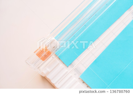 Paper trimmer cutting blue paper sheet, craft tool close up on pastel background with copy space 136780760
