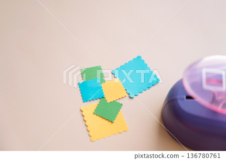 Stack of colorful paper squares with a craft punch on pastel background, scrapbooking materials with copy space 136780761