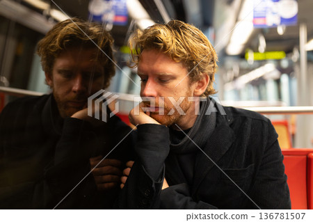Tired man commuting on public transport looking pensive Tired man commuting on public transport looking pensive 136781507