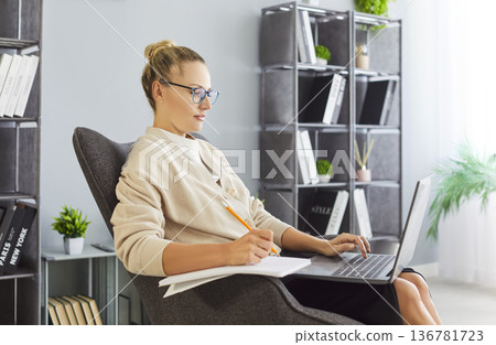 Young professional woman with glasses studying and working on laptop at home Young professional woman with glasses studying and working on laptop at home 136781723