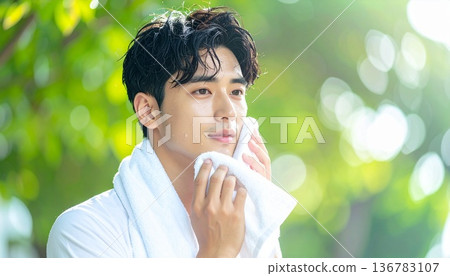 一位年輕男子戶外訓練後用毛巾擦臉的特寫。運動、運動、健身 136783107