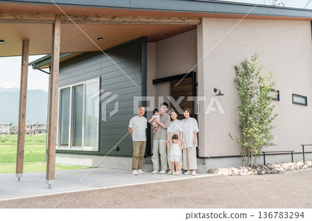 Three-generation family taking a family photo in front of their home (two-generation home) 136783294