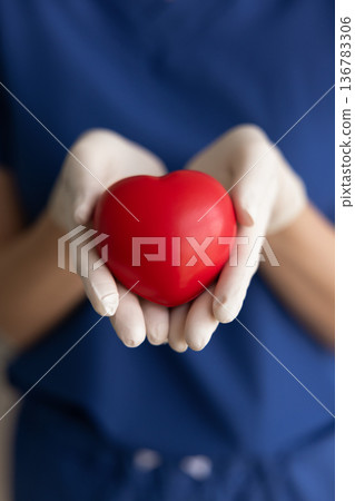 Close-up cropped image of female nurse gently holds red heart Close-up cropped image of female nurse gently holds red heart 136783306