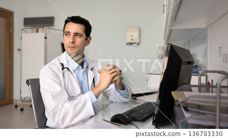Young medical specialist looks into distance with pensive expression Young medical specialist looks into distance with pensive expression 136783330