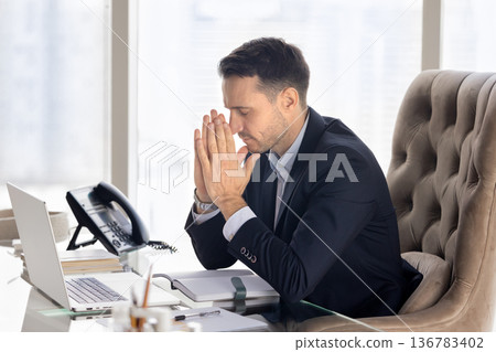 Religious business executive man praying at office workplace Religious business executive man praying at office workplace 136783402