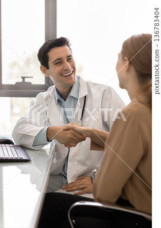 Doctor in white lab coat and female patient shaking hands 136783404