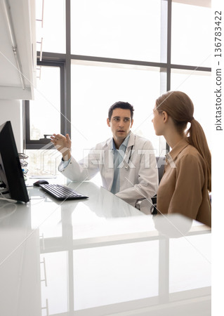 Young GP lead talk with female patient in clinic Young GP lead talk with female patient in clinic 136783422
