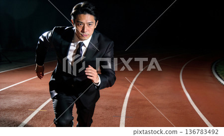 Business image of a man in a suit running at full speed overcoming obstacles in a stadium at night 136783492