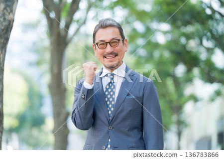 Businessman pumping his fist outdoors 136783866
