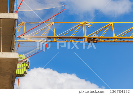 Crane lifting materials at a construction site under a bright blue sky 136784152