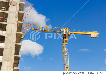 Construction site with a crane and workers under a bright blue sky during the day 136784155