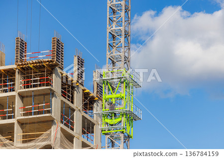 Construction site with crane and building under progress near bright blue sky 136784159
