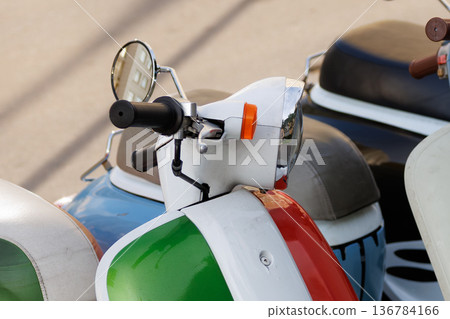 Colorful vintage scooters parked on street in a sunny day showcasing classic design and unique features Colorful vintage scooters parked on street in a sunny day showcasing classic design and unique features 136784166