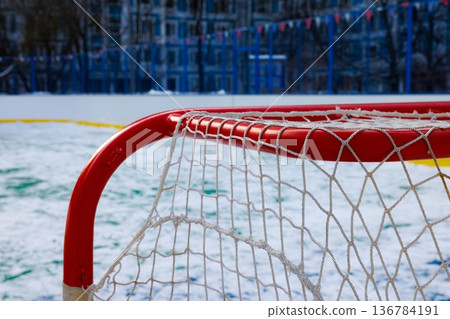 Exciting winter hockey game at a frozen outdoor rink in a lively urban neighborhood 136784191