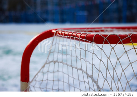 Snowy day hockey net awaits players on a frozen rink in a winter wonderland near the city 136784192