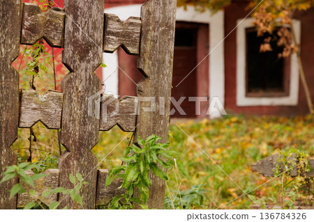 Faded wooden fence with intricate design framing a rustic building in autumn colors at sunset 136784326