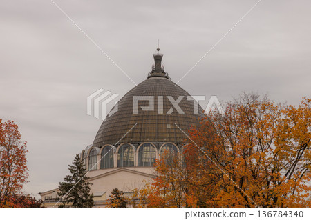 Beautiful autumn scene showcasing a historic glass dome surrounded by vibrant orange and yellow foliage Beautiful autumn scene showcasing a historic glass dome surrounded by vibrant orange and yellow foliage 136784340