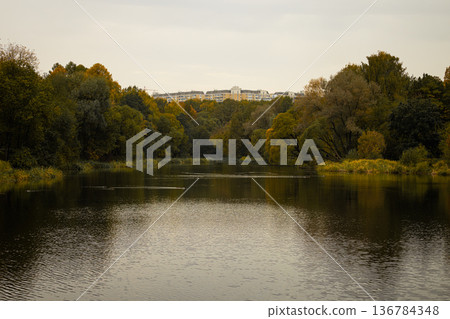 Serene autumn landscape with golden trees reflecting in calm river water at dusk Serene autumn landscape with golden trees reflecting in calm river water at dusk 136784348