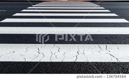 An empty urban asphalt road features white lane lines and a yellow arrow symbol painted on the tarmac to guide city traffic and pedestrian crossing transportation 136784564
