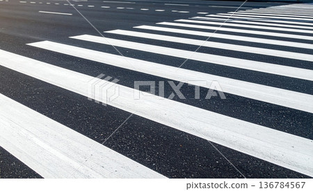 An empty urban asphalt road features white lane lines and a yellow arrow symbol painted on the tarmac to guide city traffic and pedestrian crossing transportation 136784567