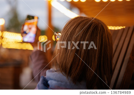 Capturing memories at a cozy evening gathering under sparkling lights 136784989