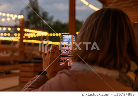 Capturing the golden glow of string lights at an evening gathering outdoors with friends Capturing the golden glow of string lights at an evening gathering outdoors with friends 136784992