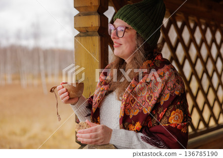 Warm autumn moments enjoyed by a smiling woman with a cup in a rustic setting 136785190