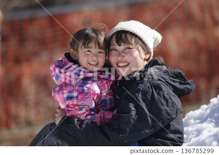 Parent and child playing in the snow Parent and child playing in the snow 136785299