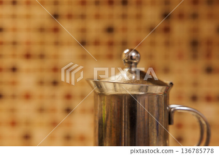 Shimmering silver coffee pot capturing warmth in a cozy kitchen setting 136785778