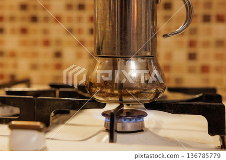 Brewing coffee on a stovetop using a traditional moka pot in a cozy kitchen setting Brewing coffee on a stovetop using a traditional moka pot in a cozy kitchen setting 136785779