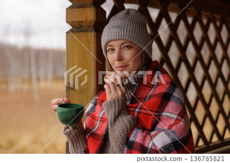 Enjoying a warm drink and a cookie while wrapped in a cozy blanket on a chilly day in a beautiful natural setting 136785821