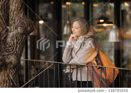 Thoughtful woman enjoying a quiet moment by a cozy cafe in the evening glow of warm lights Thoughtful woman enjoying a quiet moment by a cozy cafe in the evening glow of warm lights 136785838