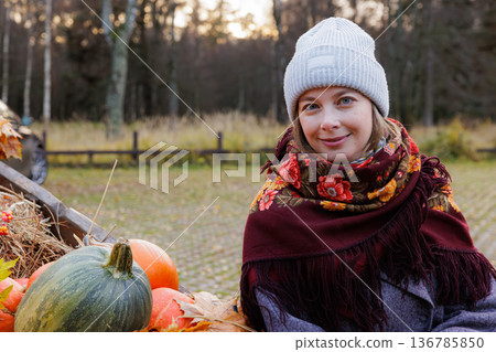 Captivating autumn day with a warm scarf and pumpkins in a serene landscape Captivating autumn day with a warm scarf and pumpkins in a serene landscape 136785850