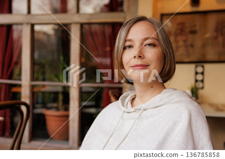 Woman enjoys a moment of calm in a cozy cafe surrounded by warm light and inviting decor Woman enjoys a moment of calm in a cozy cafe surrounded by warm light and inviting decor 136785858