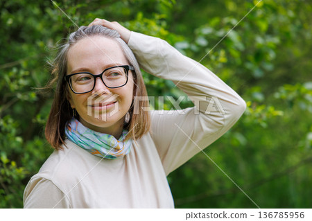 Smiling woman enjoys a sunny day outdoors surrounded by lush greenery Smiling woman enjoys a sunny day outdoors surrounded by lush greenery 136785956
