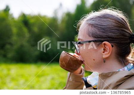Enjoying a warm cup of coffee amid lush greenery on a sunny morning in the countryside 136785965