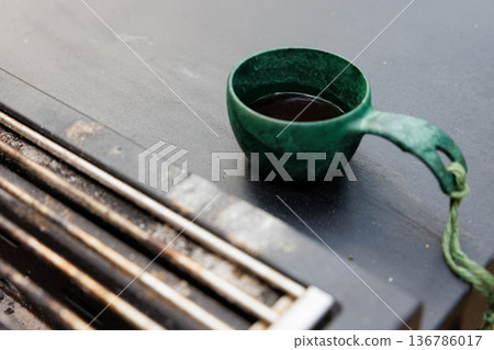 Enjoying a warm cup of dark coffee on a metal surface during a quiet moment of reflection 136786017